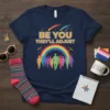 Navy t-shirt with "BE YOU THEY'LL ADJUST" text, rainbow, and colorful silhouetted figures