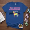 Blue t-shirt with text "Be a unicorn in a field of horses" and a colorful unicorn graphic surrounded by horse