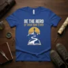 BE THE HERO OF YOUR OWN STORY quote on a blue t-shirt, featuring a mountain path leading to a silhouette