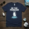 Be The Penguin t-shirt design with a cool penguin wearing sunglasses on an ice floe. White text reads "BE THE