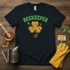 Black t-shirt with "BEEKEEPER" text in green, and a shamrock design with bees and honeycomb patterns
