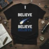 Black t-shirt with "BELIEVE BELIEVE BELIEVE" text and a blue comet graphic, representing space and inspiration