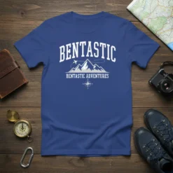 Blue t-shirt with "BENTASTIC" in arching text above mountains, an airplane, and "BENTASTIC ADVENTURES" with a compass graphic
