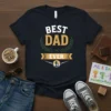 Best Dad Ever text graphic on a dark t-shirt, featuring laurel wreath and father-child silhouette design