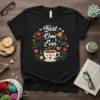 Best Omi Ever quote in white script on a black t-shirt, surrounded by a floral wreath and a teacup graphic