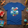 Blue t-shirt with "Birthday Boy" text and a red airplane flying around the Earth graphic