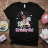 Birthday Girl text with a cute girl riding a pastel carousel horse, stars, and confetti graphic on a black t-shirt