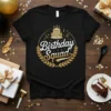 Black t-shirt with "Birthday Squad" text in white and gold, featuring a cake graphic and laurel wreath