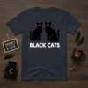 Two black cats with orange eyes sitting side-by-side, text "BLACK CATS" below, on a dark t-shirt