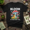 Bloom In Your Own Time t-shirt with cute cartoon caterpillar and red mushrooms, white text, bright floral accents