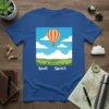 Blue t-shirt with "Blue Skies" text and a hot air balloon graphic over a green landscape