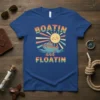 Retro "Boatin and Floatin" text with a smiling sun and boat graphic on a blue t-shirt