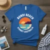 Blue t-shirt with "BONDI BEACH SYDNEY AUSTRALIA" text encircling a retro sunset over the ocean and beach