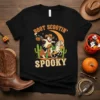 Boot Scootin' Spooky t-shirt design with a ghost cowboy riding a horse under a crescent moon with cactuses