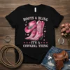Black t-shirt with "Boots & Bling It's A Cowgirl Thing" text and pink cowboy boots and hat graphic, surrounded by