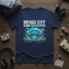 Bridge City Game Collective text on a navy t-shirt with a colorful bridge and gaming illustration, perfect for gamers