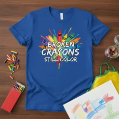 BROKEN CRAYONS STILL COLOR text design with colorful bursting crayons on a blue t-shirt