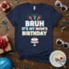 Bruh It's My Mom's Birthday text with party poppers and a cake graphic on a navy blue t-shirt
