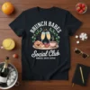 Graphic tee with "BRUNCH BABES Social Club MIMOSAS, GOSSIP, REPEAT" text, champagne glasses, croissant, and strawberries