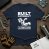 Built Different T-Shirt with white text, muscular arm, and piston graphic on navy blue fabric