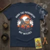 Burn The Patriarchy Not Witches t-shirt design featuring women in robes holding torches around burning ruins