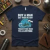 T-shirt design featuring the quote "Buy A Man Eat Fish He Day Teach Fish Man To A Lifetime" with a