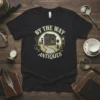 T-shirt design featuring the text "By The Way Antiques" with a vintage storefront graphic, clocks, and globe