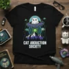Black t-shirt featuring the text "CAT ABDUCTION SOCIETY" with a cartoon cat in a UFO above mountains and smaller UFOs