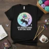 Black t-shirt with "CAT CREATIVE CHAOS & BUTTERFLY BLISS" text and a cartoon black cat playing with yarn balls and