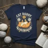 Cat Daddy Rolling Fatties text with a cute orange tabby cat playing with yarn balls, navy blue t-shirt design