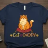 Cat DADDY t-shirt with a cute, crowned orange cat sitting on a cushion, surrounded by paw prints and text