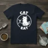 CAT EAT t-shirt design with a white cat sitting between a fork and knife in a circle, dark navy shirt