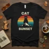 Retro vintage t-shirt design featuring a black cat silhouette against a colorful sunset and mountains, with "CAT SUNSET" text