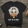 Black t-shirt with "CAT IN A BOX" text and a calico cat in a rocket-powered cardboard box graphic