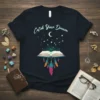 Catch Your Dream quote on a dark t-shirt with an open book, moon, stars, and dream catcher design