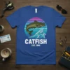Catfish Est. 1986 vintage design on a blue t-shirt featuring a catfish jumping over a wave with a retro sunset