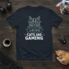 Cats and Gaming text with a stylized cat wearing headphones and holding game controllers, on a navy t-shirt