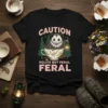 Black t-shirt with "CAUTION POLITE BUT FERAL" text and a cute possum in a teacup graphic
