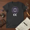 Black t-shirt with white CC logo and a purple and white triple moon mandala design, representing celestial and pagan themes