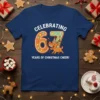 T-shirt design with white text "CELEBRATING 67 YEARS OF CHRISTMAS CHEER!" and a cartoon reindeer eating gingerbread numbers