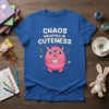 CHAOS WRAPPED IN CUTENESS text with a pink three-eyed monster holding a teacup on a royal blue t-shirt