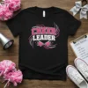 Black t-shirt with "CHEER LEADER" text in pink and white, featuring megaphone graphics and stars