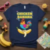 Chicken Banana text above a colorful rooster wearing sunglasses, sitting on a peeled banana on a navy t-shirt