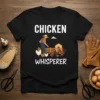 Chicken Whisperer t-shirt design with a farmer feeding chickens in a coop, featuring bold white text