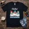 Chillin' With My Snowmies t-shirt design featuring three cute snowmen wearing hats and sunglasses, holding mugs, with festive snowflakes