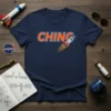 Navy blue t-shirt with the word "CHING" in orange and blue, featuring a red and white rocket ship illustration