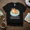 Black t-shirt featuring a cute, orange tabby cat napping on a light blue pillow with the word "CHONK" in bold