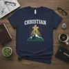 Christian Faith Mountains Cross Tee with a person standing on a mountain peak looking at a glowing cross