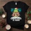 Christmas Is Here text with a frog in a Santa hat sitting on mushrooms, decorated with lights, against a winter
