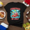 Christmas In July t-shirt design with Santa Claus grilling on a tropical beach, holding a beer and sitting on a